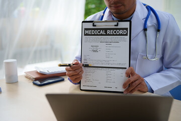 A medical doctor is working at a desk, analyzing patient data related to heart attacks and calculating medical costs to ensure accurate billing and financial management in the healthcare setting.