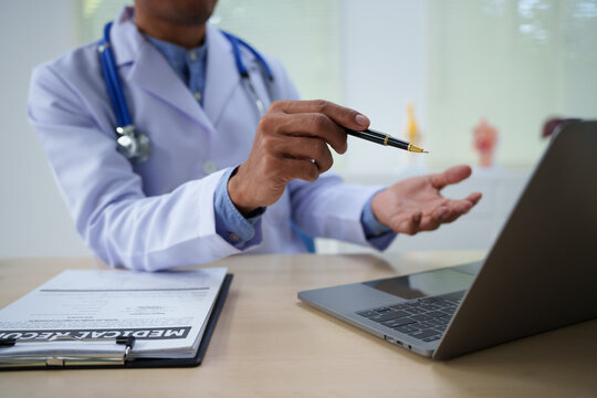 A medical doctor is working at a desk, analyzing patient data related to heart attacks and calculating medical costs to ensure accurate billing and financial management in the healthcare setting.