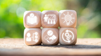 Wooden blocks with icons symbolizing capacity building concepts such as education, training, innovation, and collaboration on a natural background.