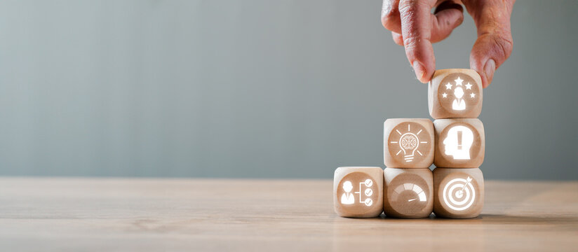 Hand arranging wooden blocks with competence concept icons, symbolizing skills, growth, and success in business and personal development.