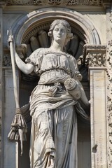 Fototapeta premium Statue of a Goddess of Wisdom and Knowledge, holding a scroll and a quill pen, standing in an ornate architectural frame.