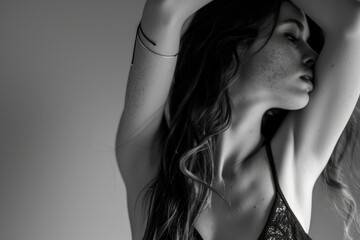 Naklejka premium Introspective Woman in Black Lace Top, Raising Hand to Neck, Against Plain Background