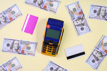 Top view of Payment Terminal, Dollars and Bank Card On Yellow Background. Concept Of Cashless Payment.