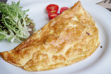 Plain Egg Omelette served with tomato and leaf on table 