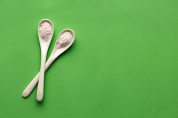 Baking soda powder in two spoons - Healthy food. Green background