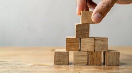 Hand Placing Wooden Block on Top of Stack