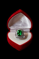 Romantic heart-shaped ring box with emerald and diamond ring inside.