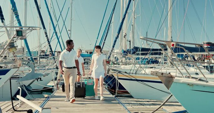 Boat port, suitcase and people walking to travel, vacation and summer trip at ocean. Luggage, pier and crew at ship dock, luxury holiday for tourism and outdoor on wood bridge at yacht harbor at sea