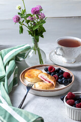 Cheesecakes with berries and tea in a cup