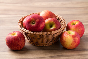 Red apple fruit (Envy apple) in basket on wooden background