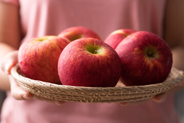Red apple fruit (Envy apple) in basket holding by woman hand, Healthy Eating
