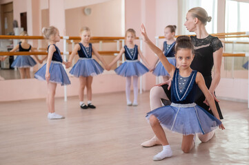 Children's ballet school. Caucasian woman teaching ballet to little girls. 