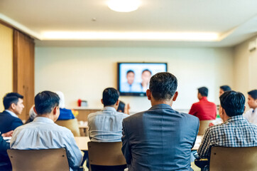 Fototapeta premium Back view of a businessman in a suit during a corporate video call