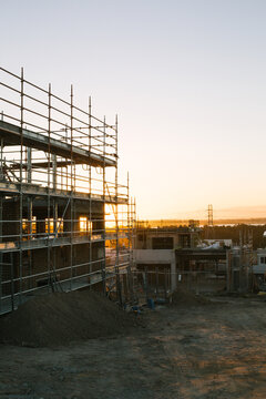 Suburban construction site with machinery and scaffolding, evening sun
