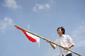 Man Holding Indonesian Flag on a Bamboo Pole