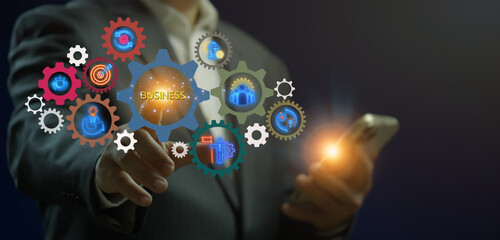 Businessman showing glowing neon line gears banner of business concept with icons of ideas, management, strategy, leadership, process, team, implementation and goals on virtual screen.