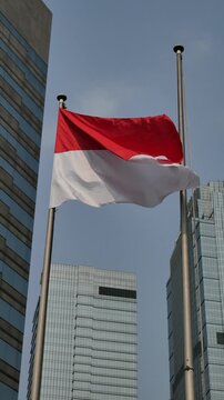  Indonesian flag flying outdoors against the backdrop of blue sky and tall buildings of the capital, BCA summitmas