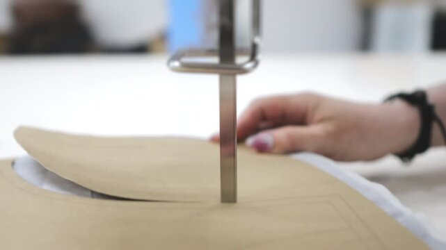 Factory for the production of clothing. A textile factory worker cuts several layers of fabric with an automatic cutting machine.