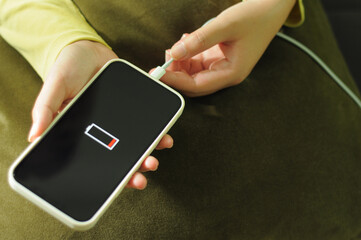 Woman hands Charging mobile phone battery with low battery. plugging a charger in a smart phone  with energy bank powerbank power charger Modern lifestyle energy technology concept