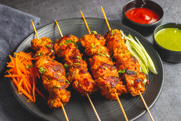 Deliciously Spiced Chicken Tikka Kabab, A Flavourful Grilled Delight with Tangy Marinade and Smoky Charcoal Aroma Serve with Mint and Tomato Chutney. Selective focus. 
