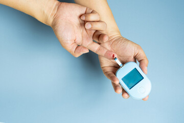 Woman's hands checking diabetes and hyperglycemia with digital blood sugar meter. Healthcare and...