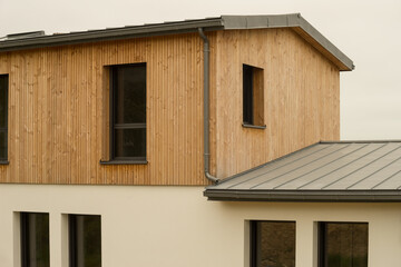 Modern architecture single-family house with flat roof made of metal titanium zinc and cladding made of untreated natural larch wood