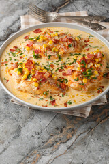 Chicken fillet with corn and bacon cooked in cheese and cream sauce close-up on a plate on the table. Vertical