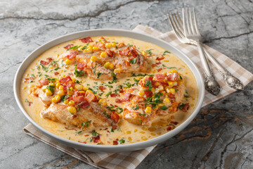 Pan-seared chicken in a creamy, spicy, street corn sauce with bacon closeup on the plate on the table. Horizontal