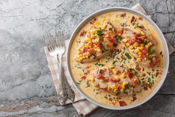 Pan-seared chicken in a creamy, spicy, street corn sauce with bacon closeup on the plate on the table. Horizontal top view from above