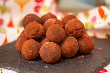 Trufas de chocolate cubiertas de cacao en polvo apiladas en una tabla de pizarra negra. Los...