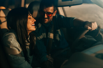 Smiling woman and man sitting in a car and enjoying driving. The woman leaned on a man's shoulder