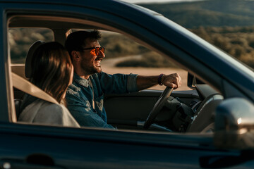 Smiling woman and man sitting in a car and enjoying driving. The woman leaned on a man's shoulder