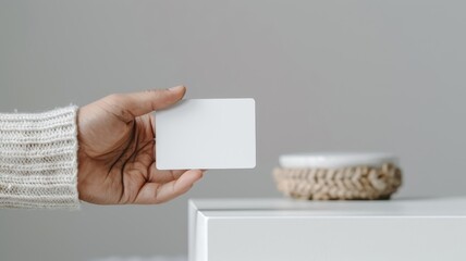 Obraz premium Close-up of a man’s hand showing a plastic credit card and a blank business card against a white studio background.
