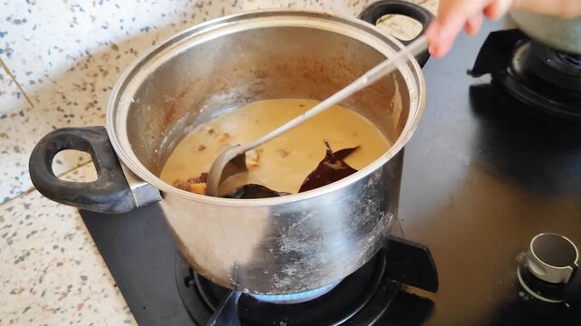 Woman's hand cooking beef curry (Gulai babat and iso sapi)