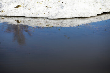 Snow-Covered Hill Reflected in Clear Winter Pond Under Bright Sunlight