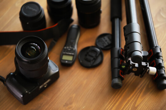 Professional Photography Equipment: DSLR Camera, Lenses, Tripod, and Accessories on Wooden Surface