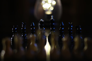 Dramatic Chess Game with Low Lighting and Illuminated Background Creating Intense Mood