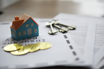 Real Estate Property Insurance Concept with Miniature House, Keys, Coins, and Policy Documents