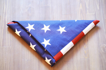 Folded American Flag on Wooden Surface with Stars and Stripes Pattern