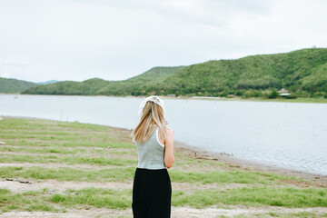 Back view of chilling young Asian female looking a amazing beautiful green mountain and lake view. Adventure travel and vacation concept.