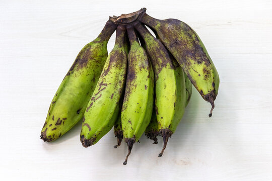 Bunch of fresh raw banana or green banana on light wooden surface.