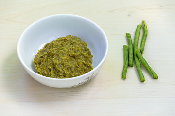 Borboti bhorta in a white bowl on wooden background, chopped yardlong bean or asparagus bean placed beside. It is healthy vegetable and also known as asparagus bean, long bean, or snake bean.