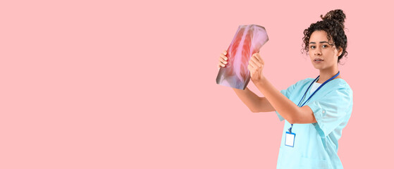 Female African-American medical intern with x-ray image of lungs on pink background