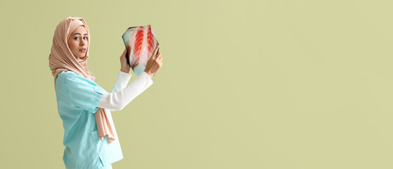 Female Muslim medical intern with x-ray image of lungs on green background