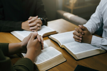 Christian and prayer. Christian group of people holding hands praying worships together to believe and Bible on a wooden table for devotional for prayer meeting concept.