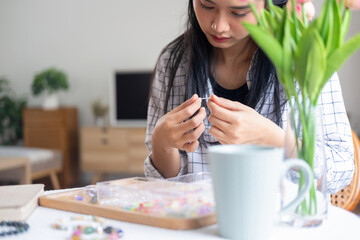 Young girl making handmade bracelets with fun and cheerfulness