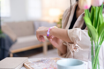 Young girl making handmade bracelets with fun and cheerfulness