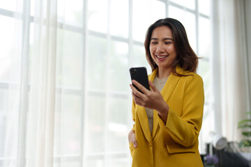 Attractive Asian businesswoman standing on the phone talking about real estate projects and chatting with happy smiles at the office.