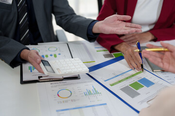 Asian business people team analyzing and brainstorming using calculators. Hand-pointing financial data on the sheet. Graph Chart showing earnings. growth teamwork process concept.