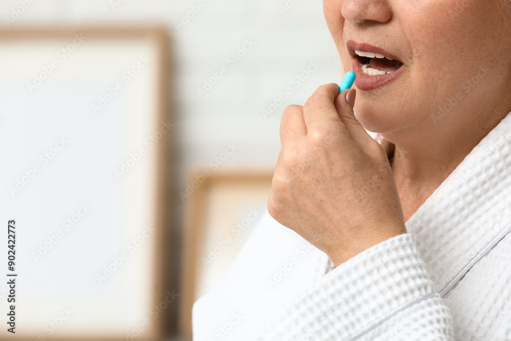 Wall mural Beautiful mature woman taking pill at home